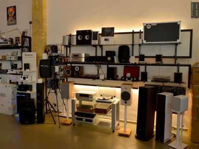 Ci guardiamo intorno. Le mensole sulla destra ospitano casse in legno di varie dimensioni e qualche amplificatore...